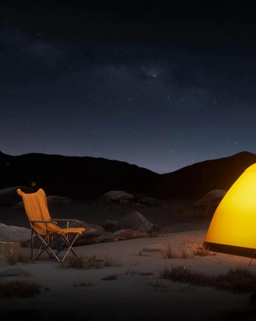 Una carpa iluminada y una silla plegable de noche